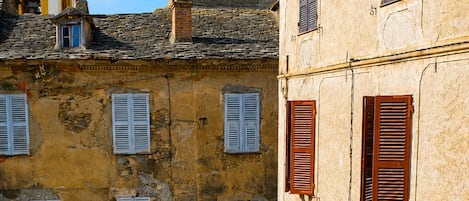 A narrow cobblestone street flanked by old buildings with arched doorways and shuttered windows.