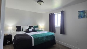 Une chambre à coucher avec un lit, des tables de chevet, une fenêtre avec des rideaux et un luminaire au plafond.