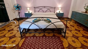 A bedroom with a bed, two bedside tables with lamps, a blue dresser, and a patterned floor. - Vacation home Hause le Gallinelle. (Assemini)