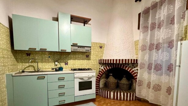 A compact kitchen with a built-in oven, a sink, and light blue cabinets. - Vacation home Hause le Gallinelle. (Assemini)