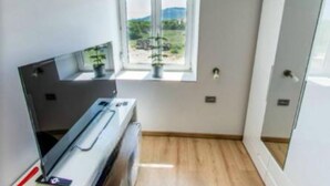Une pièce de taille modeste, avec une fenêtre, une petite table et un radiateur.