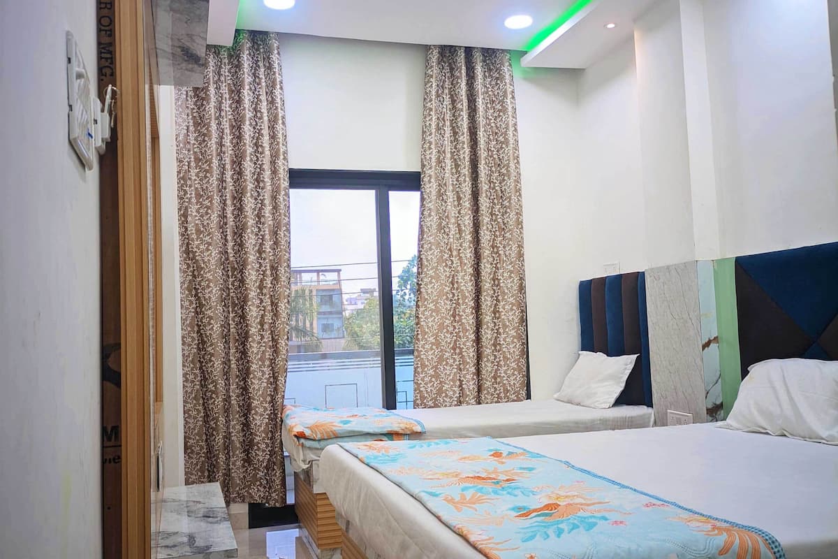 A hotel room with a bed, a window with curtains, a headboard, and a view of the outside.
