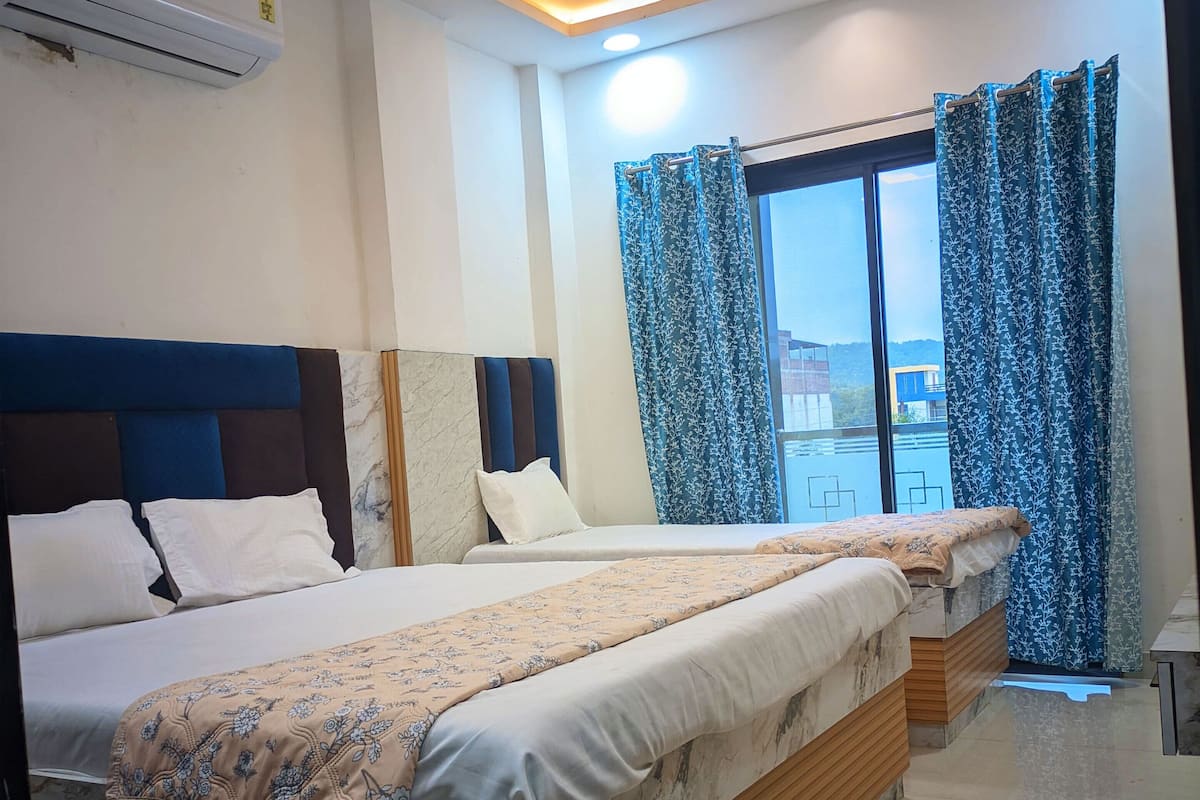 A modern bedroom with two beds, a ceiling fan, and a large window with curtains.