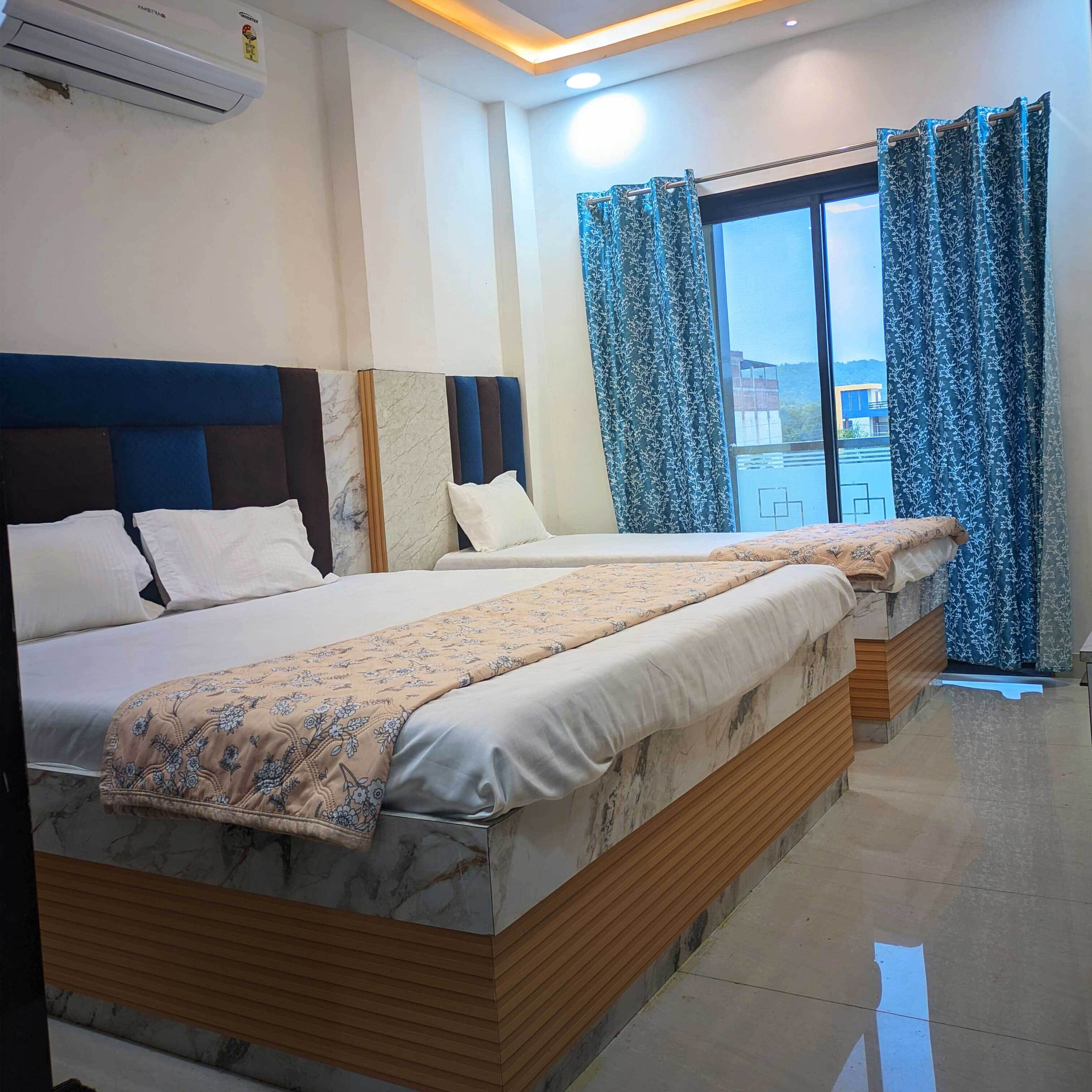 A hotel room with two beds, a large window with curtains, and an air conditioning unit on the wall.