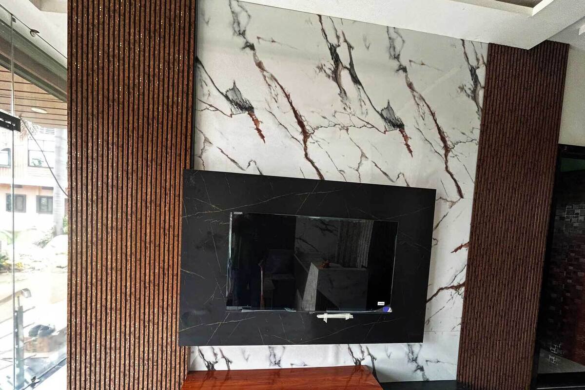 A modern living room with a large TV mounted on a marble wall, wooden paneling, and a wooden console table.