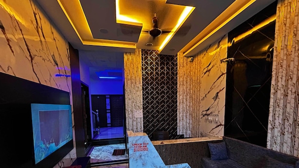 A hotel lobby with a reception desk, a television, and a patterned floor. - Hotel Moad Mudgal Palace (Khandwa)