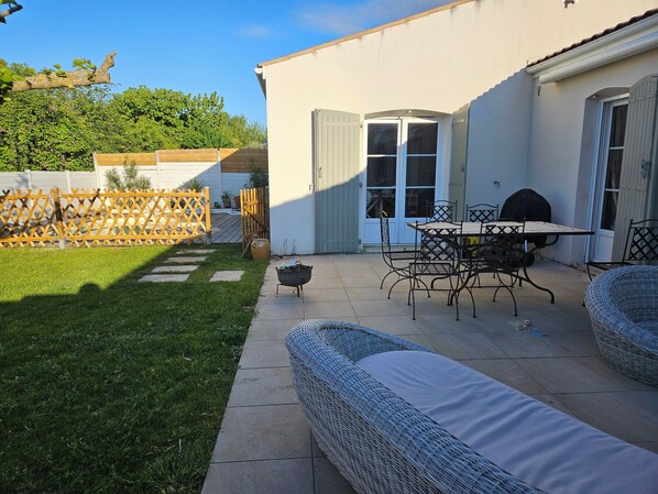 A patio with outdoor furniture, a grill, and a fenced garden area.