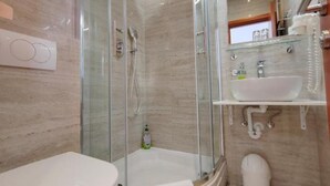 Ein modernes Badezimmer mit einer Duschkabine, einem weißen Waschbecken und einer Toilette.
