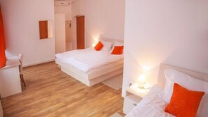Ein Hotelzimmer mit zwei Betten, Holzboden und weißer Farbgestaltung.