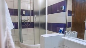 Une salle de bain moderne avec une douche à parois de verre, un lavabo blanc et un miroir au-dessus du lavabo.
