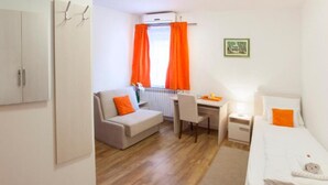 Una habitación de hotel compacta con cama, escritorio, silla y sofá.