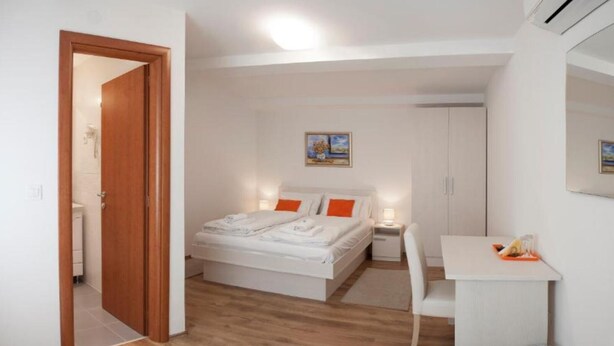 Een slaapkamer met een bed, nachtkastje, stoel en bureau.