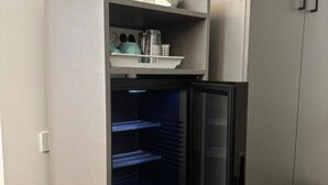Une cuisine équipée d’un réfrigérateur encastré, d’une étagère pour ranger les ustensiles de cuisine et d’un four à micro-ondes.
