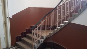 Eine Treppe mit Metallgeländer, Schachbrettfliesen und braunen Wänden.
