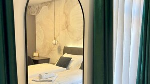 A hotel room with a bed, a nightstand, a lamp, and a view through a mirror. - Rooms Lidija 32 - Double Deluxe Room (11) (Zagreb)