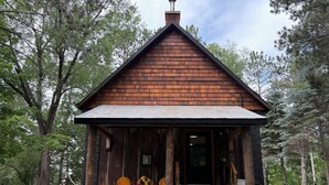 A rustic wooden cabin with a porch, surrounded by trees. - Cozy Lake Cabin in Restored 1894 Schoolhouse—Perfect Escape. (Aitkin)