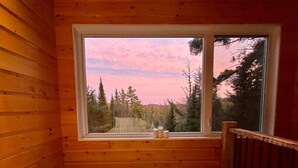 A room with wooden walls and a large window. - Cozy Cabin on Oxtongue River; Wolf Cottage (Huntsville)