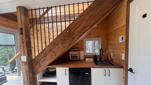A compact kitchen with wooden beams, a built-in oven, and a sink. - Cozy Cabin on Oxtongue River; Wolf Cottage (Huntsville)