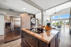 A modern kitchen with a stainless steel refrigerator, built-in oven, and a large island with a sink. - Rum Reef, 6 bedroom house in North Side, pool, private beach, kayaks, bikes. (North Side)