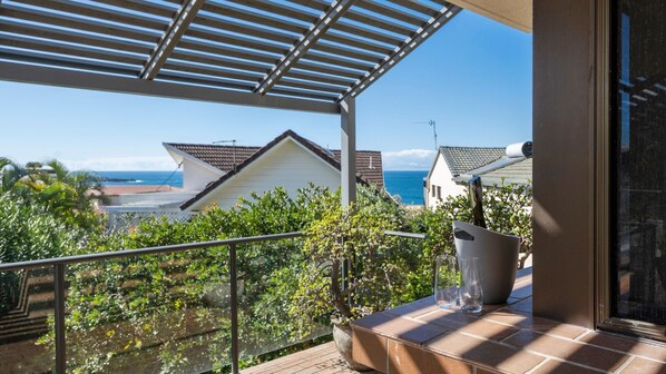 A balcony with a view of the sea and neighboring houses.