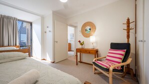 Une chambre à coucher comprenant un lit, une chaise, une table et une lampe fixée au mur.