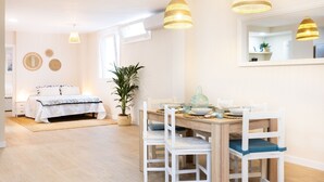 Una habitación luminosa y espaciosa con una mesa de comedor de madera, sillas blancas y un espejo grande.