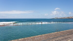 Una piscina con vistas al océano y un paisaje urbano de fondo.