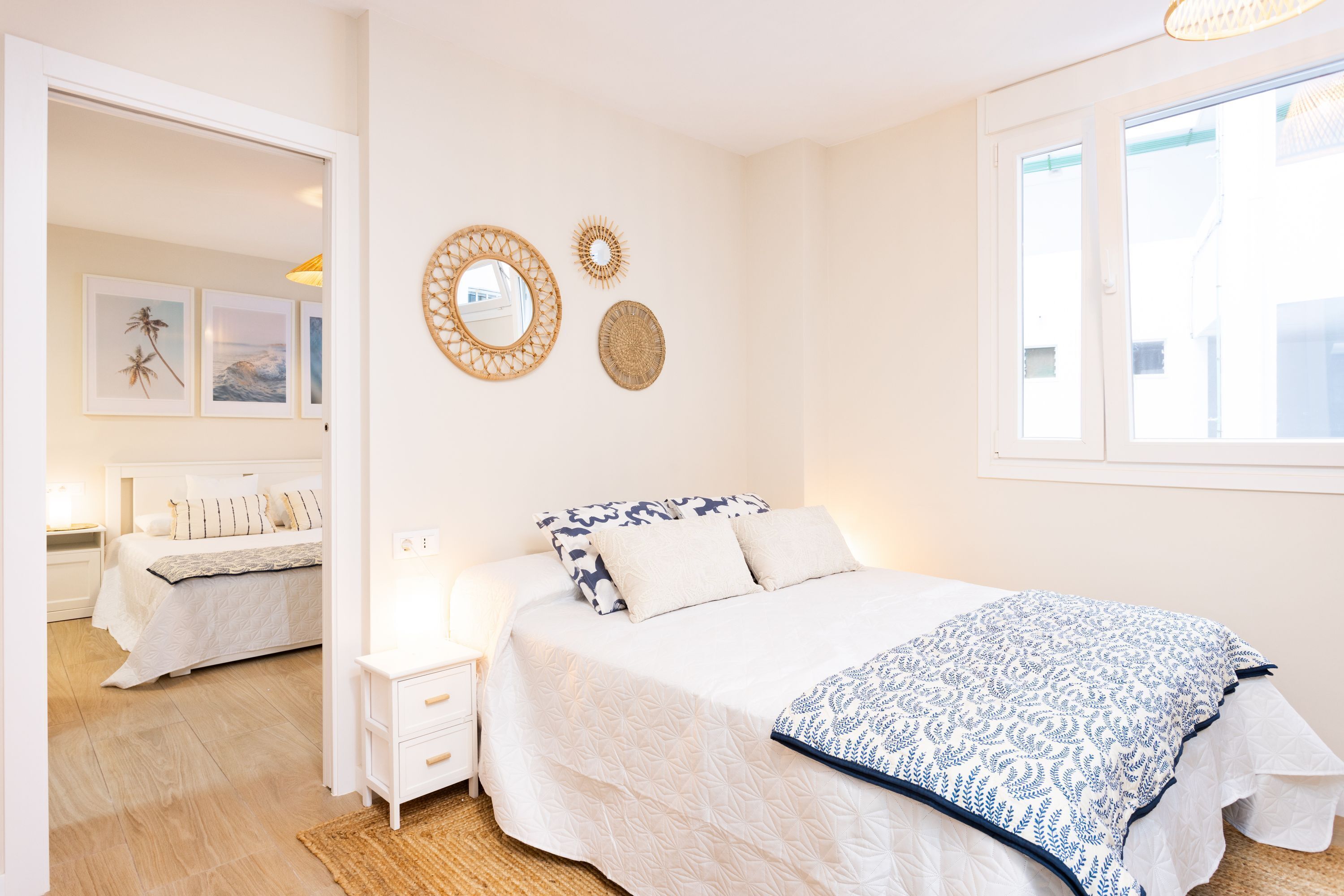 A bedroom with a large bed, bedside tables, a mirror, wall art, and a window.