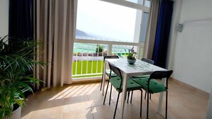Un balcón con una mesa y sillas, una planta en maceta y vistas a un paisaje verde.