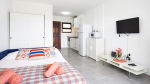 Une chambre d’hôtel équipée d’un lit, d’un bureau, d’une télévision et d’une kitchenette.