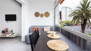 Un salon moderne avec un canapé, une table à manger et un téléviseur fixé au mur.