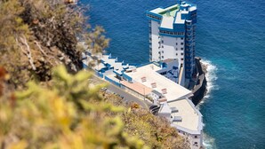 Un hotel costero con una imponente estructura de torre, una terraza en la azotea y vistas al mar.