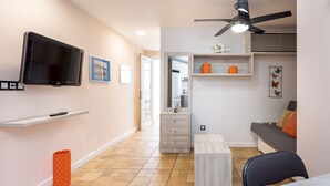 Una sala moderna con televisor de pantalla plana, ventilador de techo, sofá y comedor.