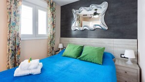 Un dormitorio con cama, espejo y mesita de noche.