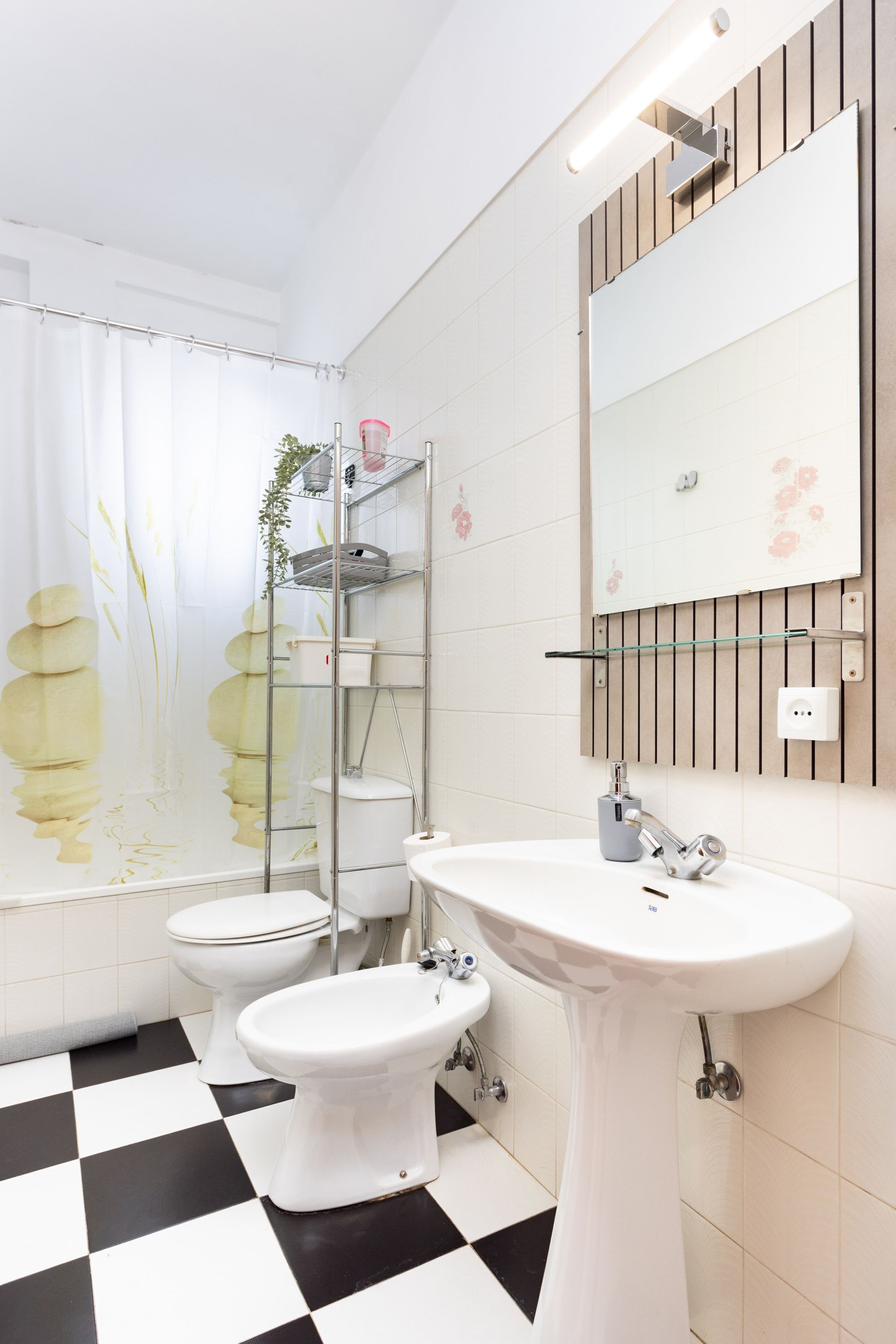 A bathroom with a checkered floor, a white sink, a toilet, and a shower with a curtain.