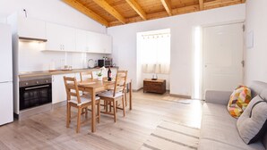Een moderne keuken met houten balken, witte kasten en een eethoek met een houten tafel en stoelen.