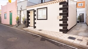 Een gebouw met een beige gevel, zwarte raamkozijnen en een betegelde entree.