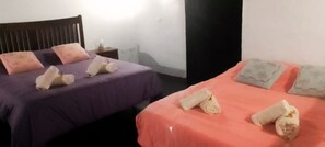 Two beds with purple and orange bedding, each with rolled towels and pillows. - Casa Rural El Naranjero (El Tanque)