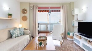 A modern living room with a sofa, coffee table, TV, and a balcony with curtains. - Apartamento Coral Sunsent View (Tacoronte)