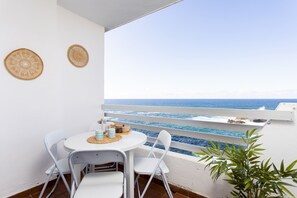 A balcony with a white table and chairs, a woven placemat, and two decorative wall hangings. - Apartamento Casa Calma (Tacoronte)