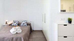 A modern hotel room with a neatly made bed, a bedside table with a lamp, a small cabinet, and a potted plant. - Apartamento Brisa del Mar (Tacoronte)