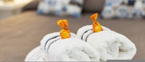 A neatly arranged set of white towels with a golden tag, placed on a wooden surface.