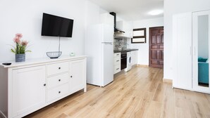 A modern kitchen with white cabinetry, a built-in oven, and a flat-screen TV mounted on the wall. - Brisa Marina (Tacoronte)