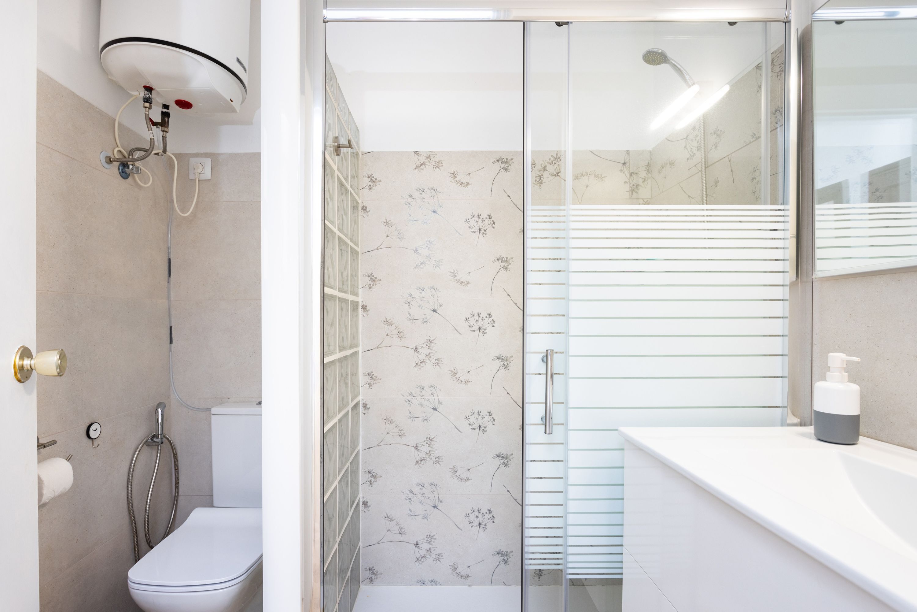 A modern bathroom with a shower, toilet, and sink.