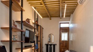 A cozy living room with a sofa, a TV, a laptop on a wooden desk, and a patterned floor. - Luxury Casita Calle 47 Gastronomic Corridor (Mérida)