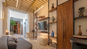 A modern living room with a sofa, a TV, wooden shelves with decorative items, and a patterned rug. - Luxury Casita Calle 47 Gastronomic Corridor (Mérida)