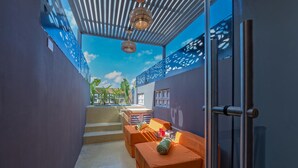 A modern outdoor seating area with orange cushions and a glass door leading to a pool. - Luxury Casita Calle 47 Gastronomic Corridor (Mérida)