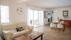 Un salon spacieux comprenant un canapé, une table basse et un coin repas avec des chaises et une table dressée.