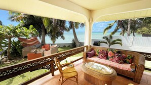 A balcony with wicker furniture, a cushioned sofa, and a view of the ocean. - Villa Hereiti by ENJOY VILLAS / 3 bdrm AC /3 bath /private pool and front lagoon (PAPETOAI)