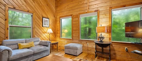L’intérieur d’un chalet accueillant, avec un plafond en bois, un canapé, une table et un téléviseur.